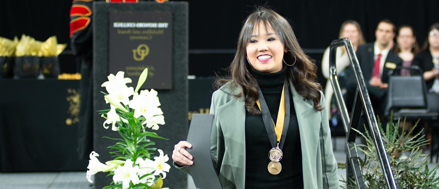 Student smiles while walking off stage after getting medallion awards at 荣誉学院 ceremony